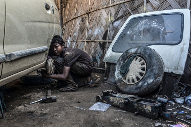 Em Ural Rahul, 15 tuổi, đang làm việc trong một garage ở Dimapur, Ấn Độ vào tháng 6/2013. Theo ước tính của ILO, trên thế giới hiện có khoảng 215 triệu trẻ em phải lao động để kiếm sống, nhiều em phải làm việc toàn thời gian - Tin: WSJ/Ảnh: Zuma Press.
