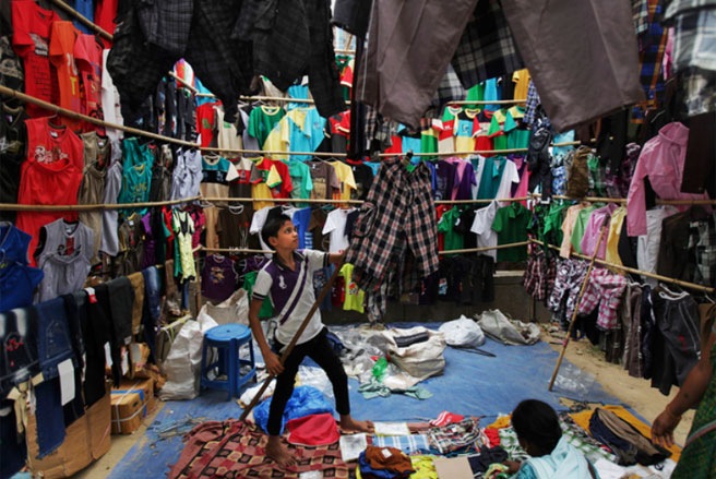 Một cậu bé người Ấn Độ đang bày quần áo để bán ở New Dehli vào tháng 6/2013. Ngày Thế giới phòng chống lao động trẻ em do ILO chọn bắt đầu có từ năm 2002 - Tin: WSJ/Ảnh: AP.