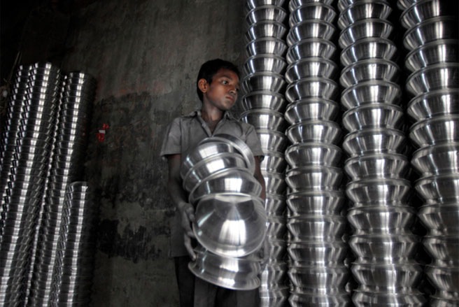 Một cậu bé đang làm việc trong một nhà máy kim loại ở Dhaka, Bangladesh. Chủ đề của ngày Thế giới phòng chống lao động trẻ em năm nay là “Hãy nói không với lao động trẻ em làm thuê giúp việc gia đình” - Tin: WSJ/Ảnh: AP.