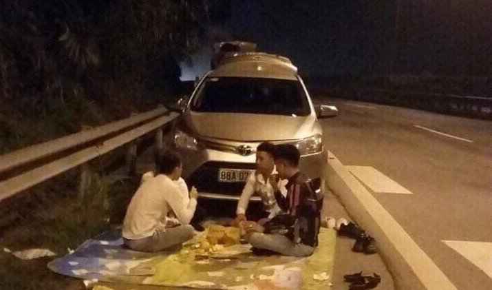 Nhóm thanh niên trải bạt ngồi ăn uống trên cao tốc.