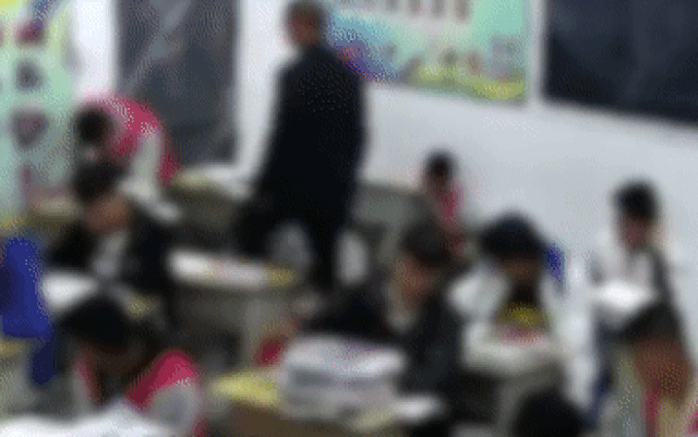 Thầy giáo dùng chân đá vào người nam sinh ngồi ở bàn trên.