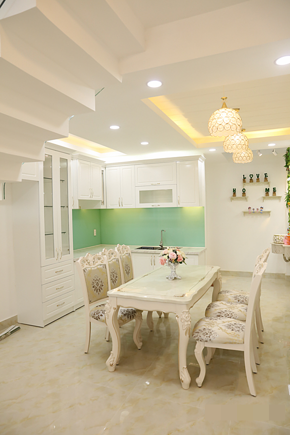 Khu vực bếp với bộ bàn ăn 6 ghế kiểu cổ điển, tủ bếp gam trắng hài hòa với tổng thể ngôi nhà.