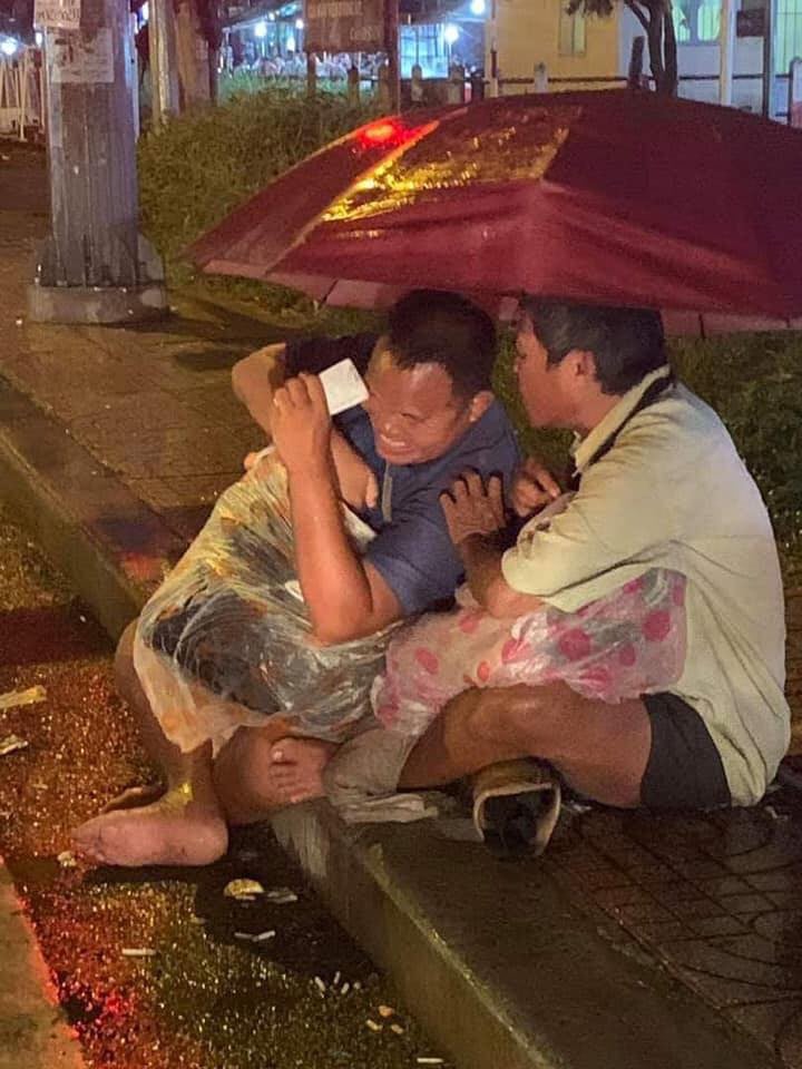 Hai người đàn ông khiếm thị mưu sinh dưới mưa.