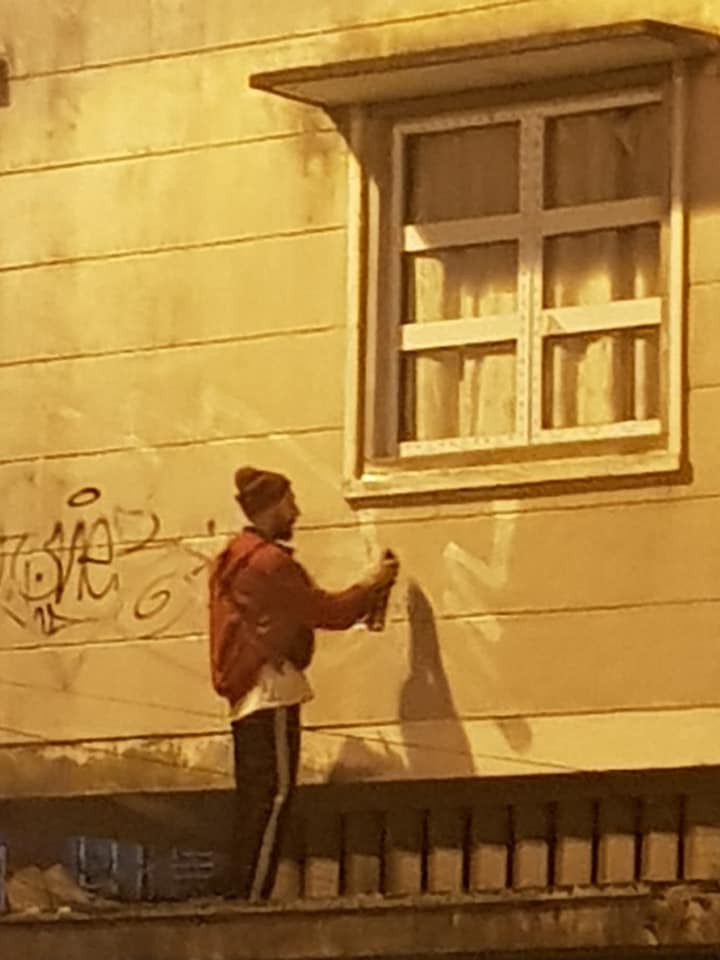 Thanh niên trèo lên tường vẽ bậy.
