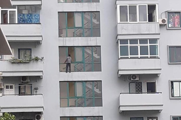 Người đàn ông đu bám ngoài cửa sổ chung cư.