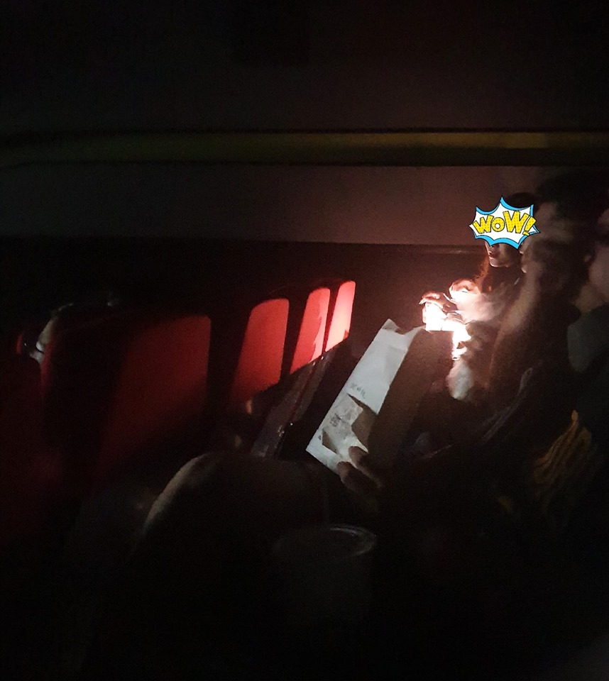 2 cô gái mở đèn flash để trang điểm trong rạp chiếu phim.