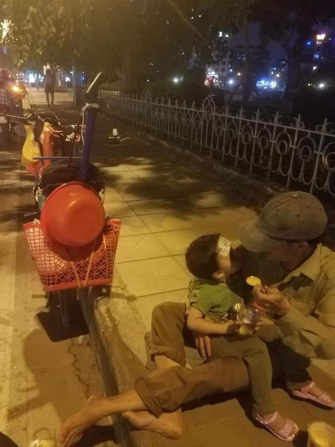 Hình ảnh người cha đút cháo cho con nhỏ trên đường.