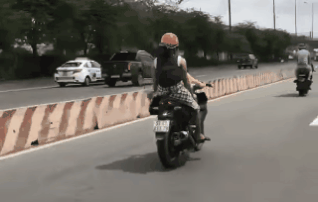 Hình ảnh người mẹ để con nhỏ lái xe máy trên đường.