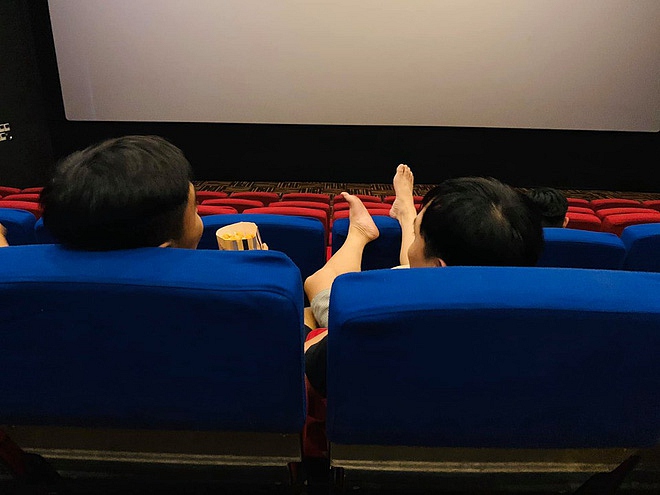 Hình ảnh người đàn ông gác chân lên ghế trong rạp phim.