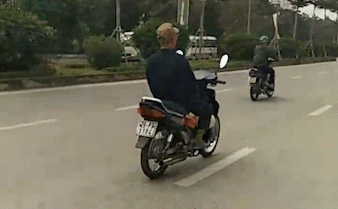 Người đàn ông lái xe máy bằng chân lao vun vút trên đường.