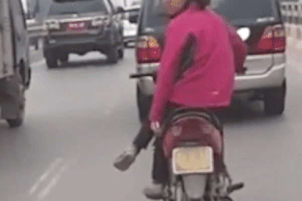 Khoảnh khắc người phụ nữ phóng xe lạng lách vào giữa 2 chiếc ô tô làm ai cũng hoảng hốt. Hình ảnh cắt từ clip.
