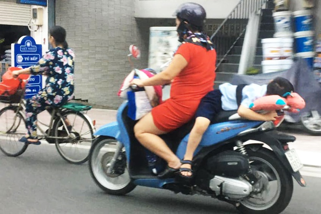 Người phụ nữ để con nhỏ nằm ngủ trên yên xe máy rồi chạy băng băng trên đường.