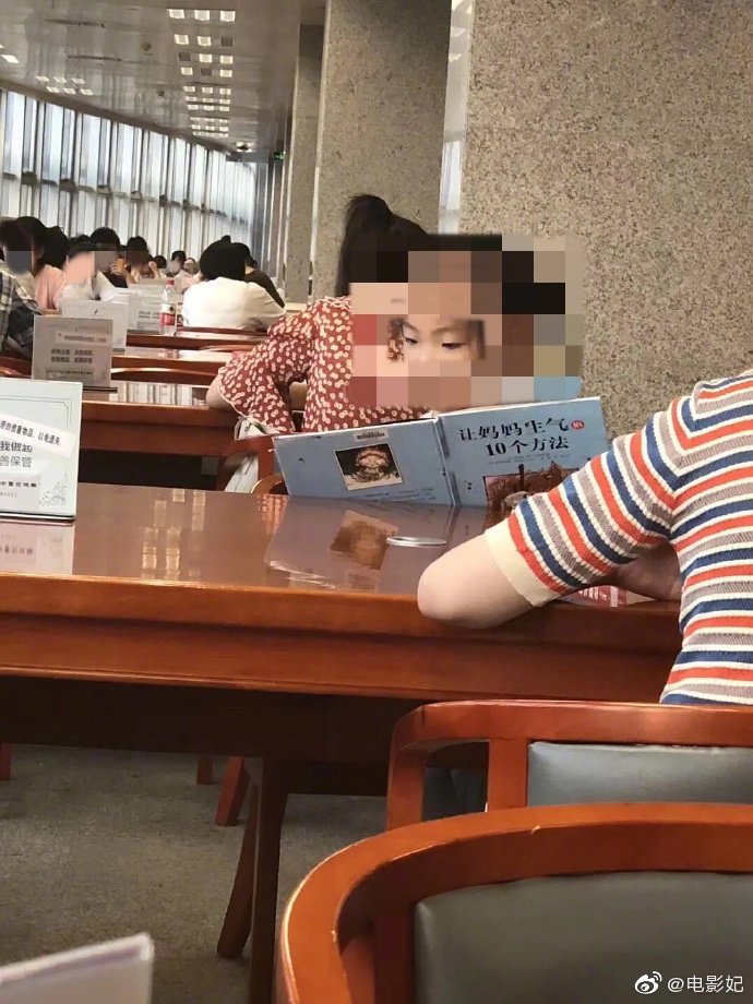 Bé gái chăm chú đọc sách trong thư viện.
