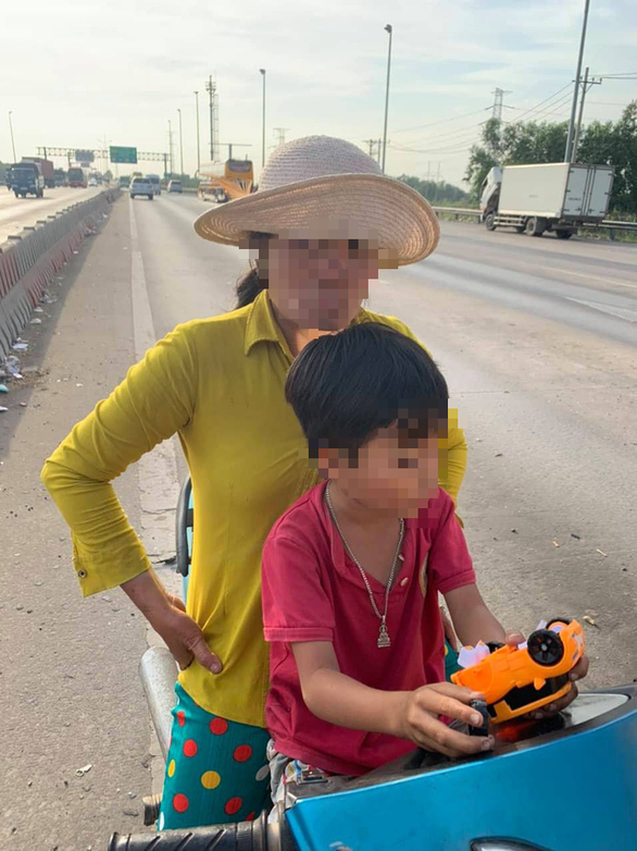 Người phụ nữ và con trai dừng xe máy trên đường cao tốc.