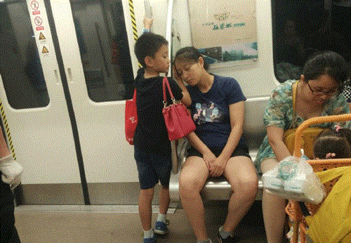 Bé trai kê tay lên tấm kính cho mẹ dựa đầu vào ngủ.