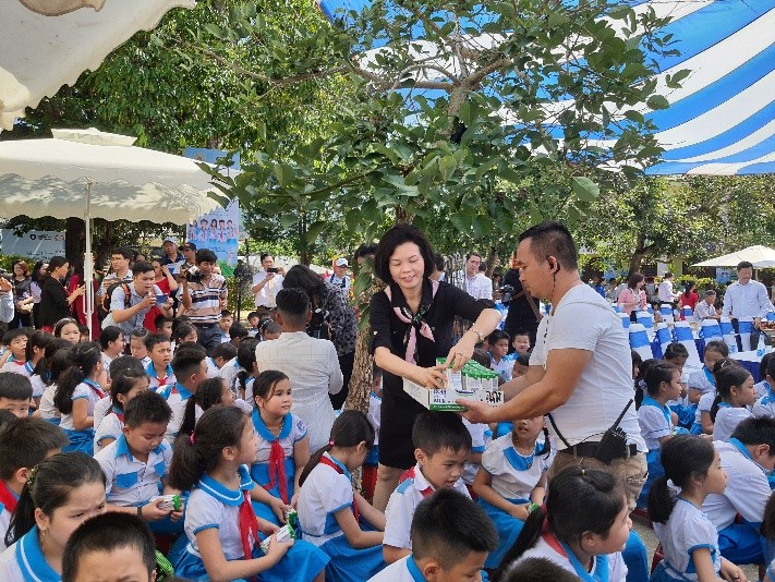 Các em học sinh trường Kim Đồng nhận những hộp sữa từ Vinamilk và các đại biểu tham dự chương trình