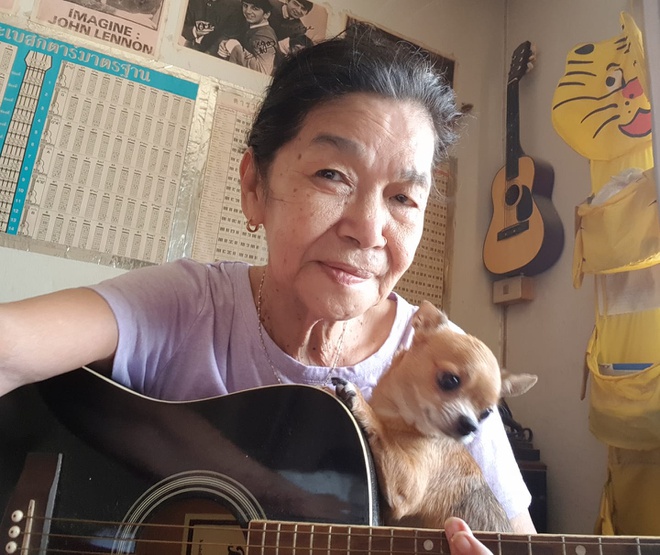 Hình ảnh cụ bà ngồi ôm chú chó nhỏ, vừa đàn vừa hát thu hút sự chú ý của cộng đồng mạng (Ảnh: FBNV)