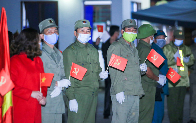 Lực lượng dân quân tự vệ và dân phòng cầm cờ chờ đón giây phút dỡ bỏ lệnh cách ly xã hội (Ảnh: Người lao động)