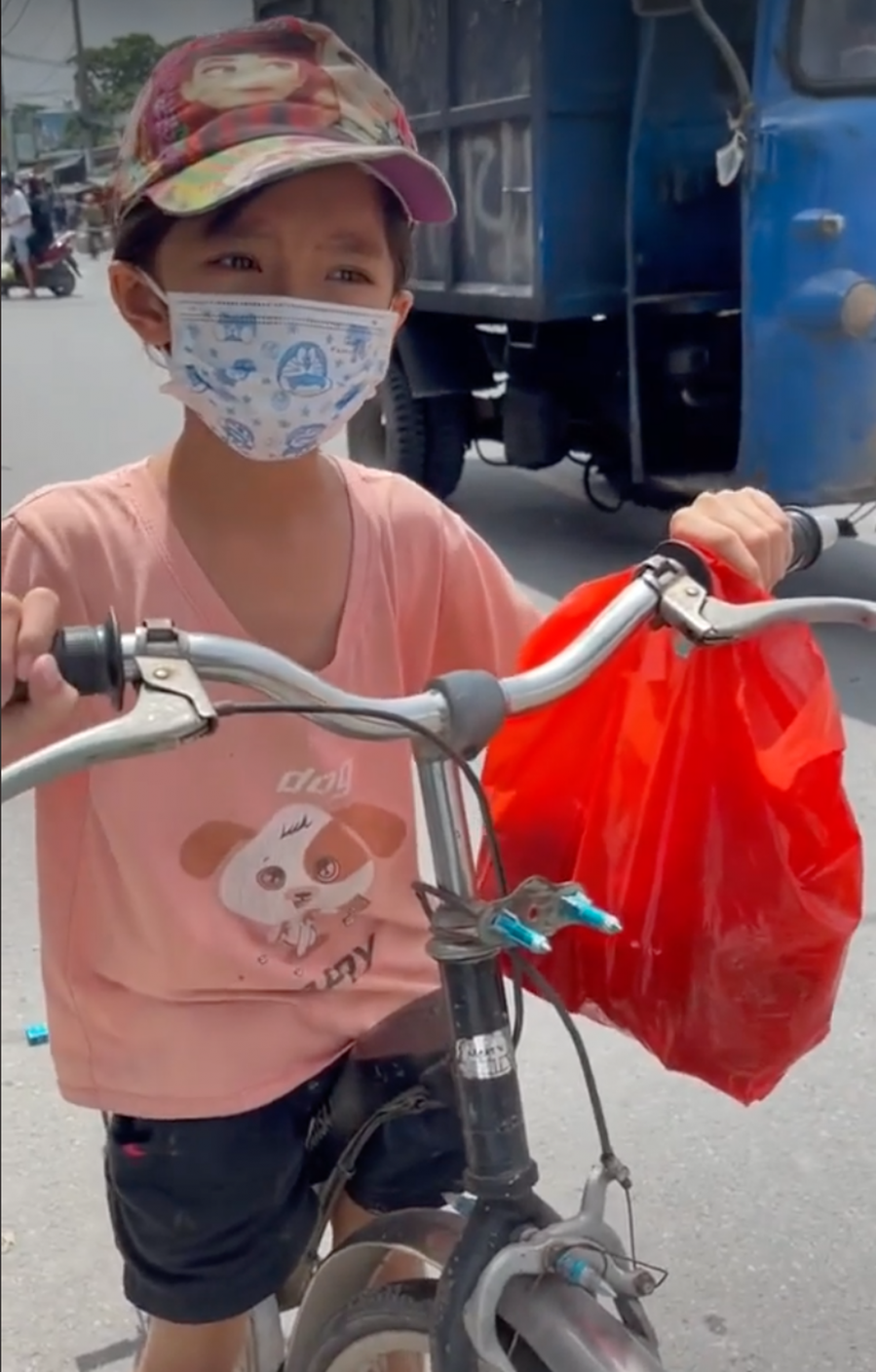 Hình ảnh cô bé đạp xe theo người mang đồ từ thiện, xin sữa cho em (Ảnh: Pháp luật và Bạn đọc)
