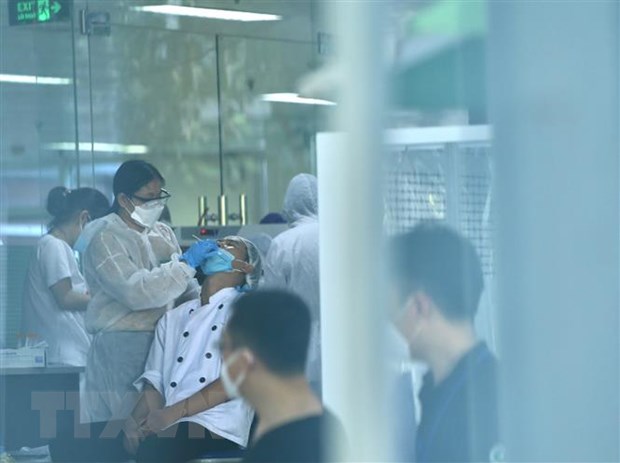Lực lượng y tế lấy mẫu sàng lọc SARS-CoV-2 cho những người trong tòa nhà D, Bệnh viện Việt Đức. (Ảnh: TTXVN)
