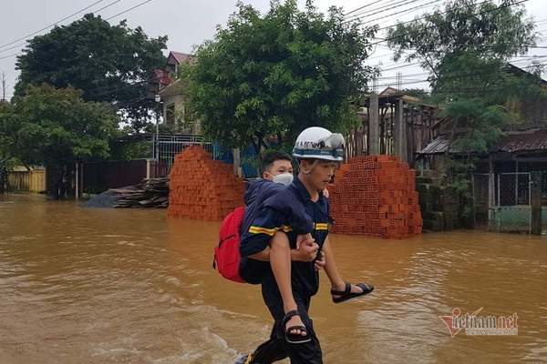 Lực lượng dân phòng, công an địa phương chia nhau cõng các em học sinh ra khỏi vùng ngập lụt đến vị trí an toàn và giao lại cho phụ huynh. Ảnh: VietNamNet