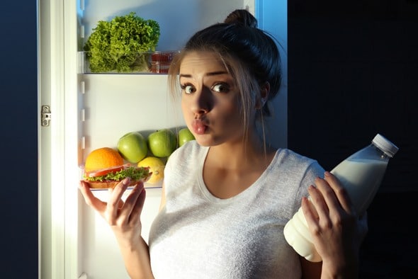 young-woman-wondering-whether-to-eat-food-before-going-to-bed
