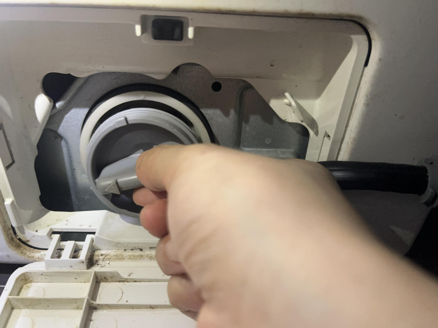 Vặn phần nắp của bộ phận lọc cặn bẩn trên máy giặt ra.