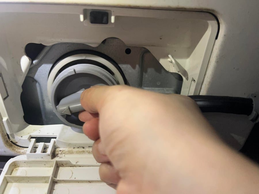 Vặn phần nắp của bộ phận lọc cặn bẩn trên máy giặt ra.