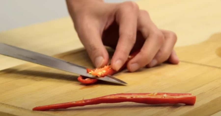 Dùng dao cắt đôi quả ớt theo chiều dọc rồi loại bỏ phần hạt ớt.