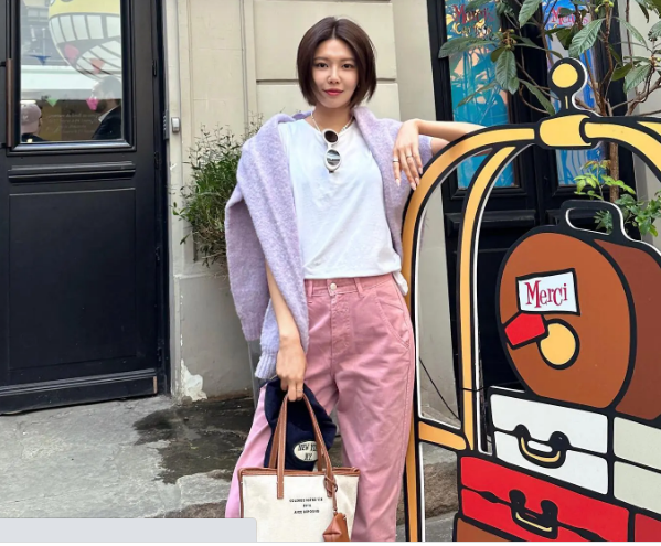Sooyoung kết hợp áo thun trắng với quần màu hồng pastel và tô điểm áo len quàng vai màu tím nhạt. Bộ trang phục của Sooyoung có sự tươi sáng, nổi bật mà vẫn trang nhã. 

