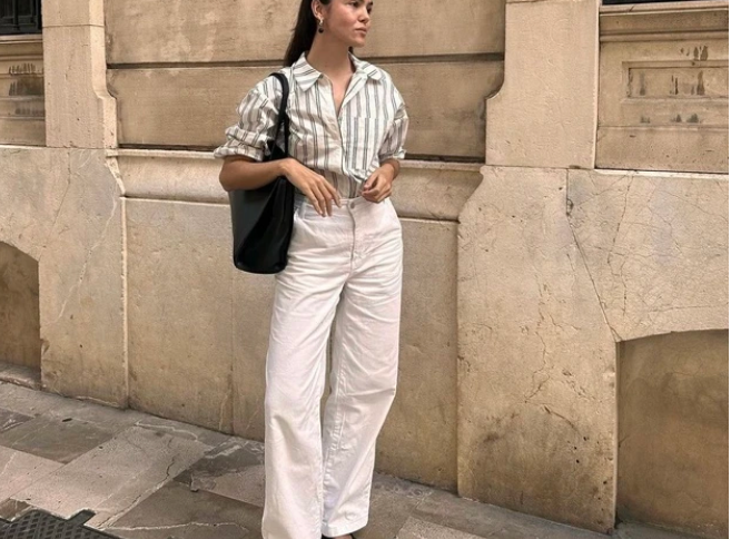 Cô nàng này phối áo kẻ sọc trắng cùng quần trắng denim, giày búp bê và túi tote đen đơn giản. Phong cách theo xu hướng minimalist (tối giản) mang đến một sự nổi bật thoải mái.    