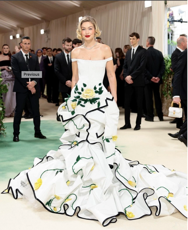 Gigi Hadid diện váy màu trắng của thương hiệu Thom Browne. Điểm nhấn của outfit nằm ở phần hoa cách điệu tinh tế cùng với những đường viền đen đã làm nổi bật thêm vẻ đẹp của nàng siêu mẫu.

