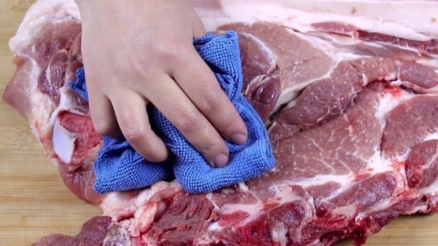 Người bán thịt dụng khăn lau loại bỏ hoàn toàn máu bám dính vào thịt lợn
