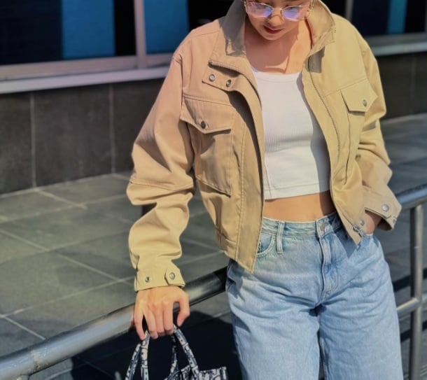 Mai Ngọc gợi ý một outfit năng động, khỏe khoắn với áo crop top trắng, quần jeans xanh và áo khoác ngắn màu be. 