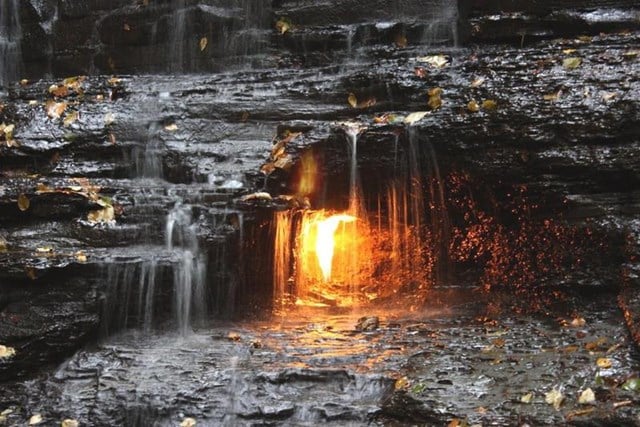 Tại công viên Chestnut Ridge, New York, có một điều tưởng chừng như nghịch lý: giữa dòng thác nước mát lạnh lại tồn tại một ngọn lửa đang cháy rực rỡ