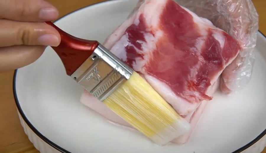 Thoa một lớp dầu mỏng lên bề mặt miếng thịt lợn.