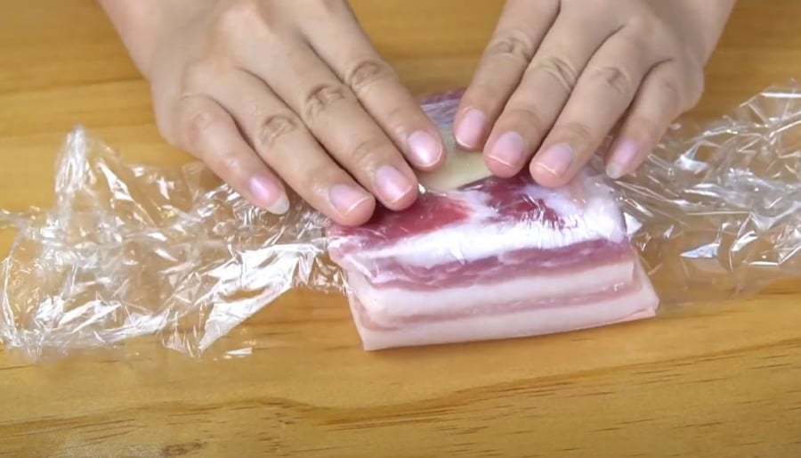 Dùng màng bọc thực phẩm gói kín miếng thịt.