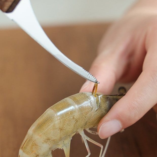 Dùng dao nhỏ rạch nhẹ sống lưng tôm để lộ sợi chỉ đen – thao tác quan trọng giúp món tôm sạch và đẹp mắt hơn.