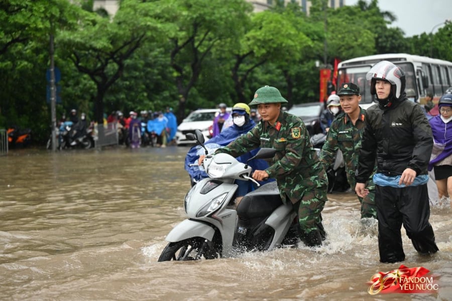 Khu vực Mỹ Đình sáng nay nước dâng cao quá nửa bánh xe. Nhiều phương tiện khó di chuyển, chết máy. Trước tình huống này, nhiều chiến sĩ đang thực hiện nhiệm vụ tập luyện diễu binh diễu hành kỷ niệm 80 năm Quốc khánh đã hỗ trợ người dân đi qua vùng ngập sâu. (Ảnh: doisongphapluat/nguoiduatin)