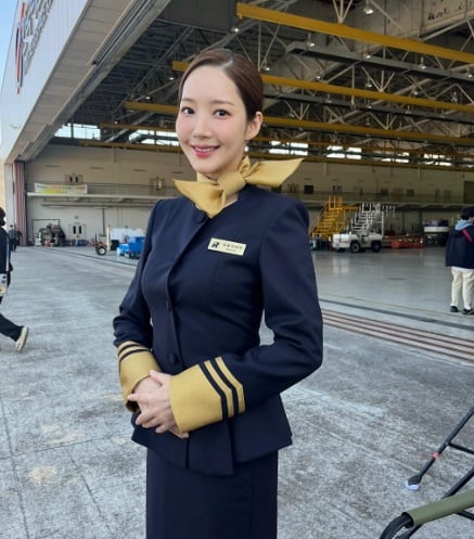 Khi giả dạng tiếp viên hàng không, cô chọn đồng phục navy phối khăn cổ vàng