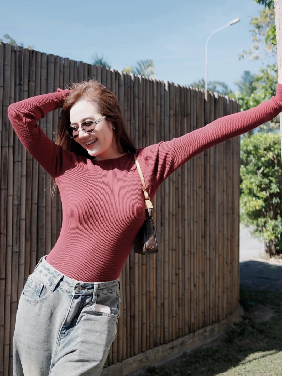 Áo len mỏng màu đỏ đô phối cùng jeans xanh tạo nên vẻ ngoài trẻ trung nhưng vẫn giữ được sự nhã nhặn.