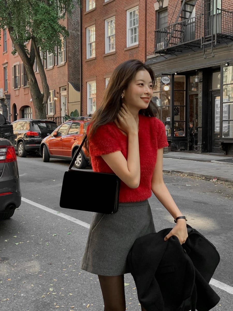 Áo len đỏ cộc tay kết hợp cùng chân váy dạ ngắn màu xám mang đến tổng thể sành điệu và thanh lịch. 