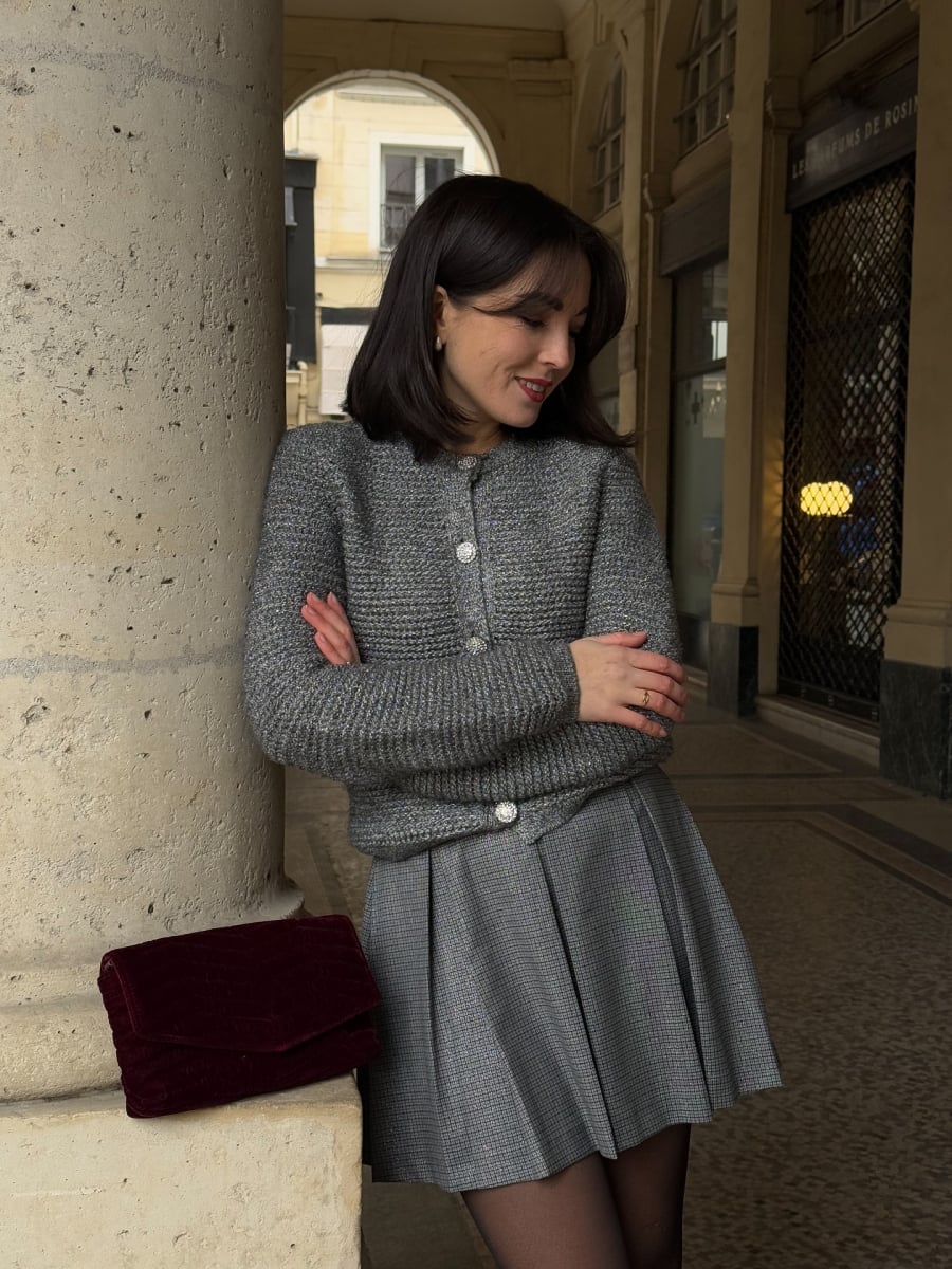 Điểm đặc trưng nằm ở tỷ lệ: váy không quá ngắn, áo len không quá bó, tất cả đều vừa đủ để tạo cảm giác thanh lịch.