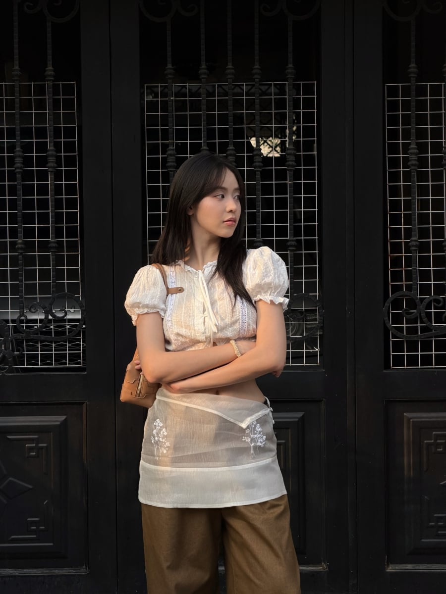 Chi tiết váy tạp dề layering phía ngoài trở thành điểm nhấn thú vị, giúp bộ trang phục thêm phần bắt mắt mà vẫn gọn gàng, không rối.    