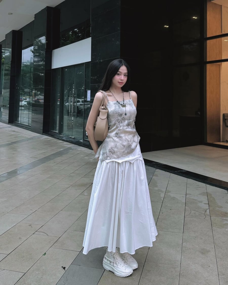 Một trong những outfit thu hút ánh nhìn nhất là sự kết hợp giữa áo hai dây họa tiết và chân váy chữ A. Set đồ mang đến cảm giác nữ tính, bay bổng nhưng không hề “bánh bèo”. 