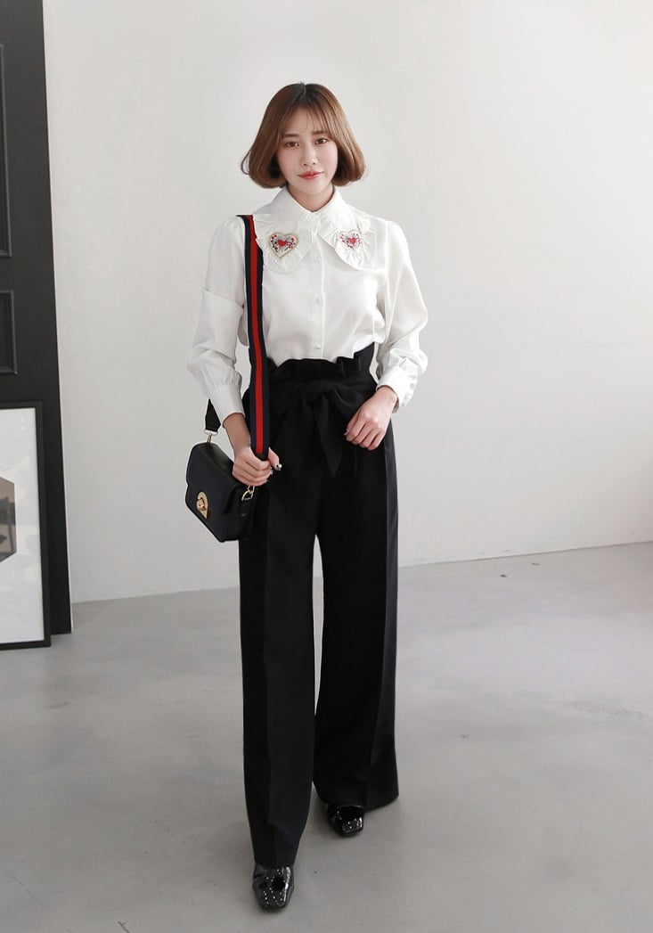 Những gam màu cơ bản như trắng, be hoặc xanh nhạt giúp tạo cảm giác nhẹ nhàng, đồng thời làm nổi bật sự thanh lịch vốn có của quần đen.