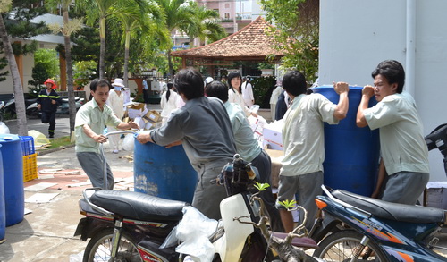 Các nhân viên công ty nỗ lực đưa các thùng hóa chất ra khỏi khu vực cháy. Ảnh: Tuổi Trẻ