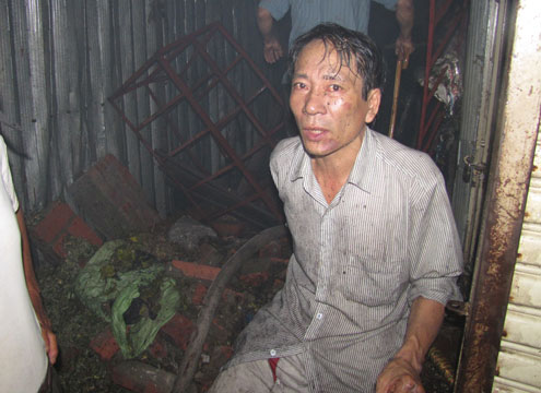 Anh Trần Văn Trọng, chủ cửa hàng thuốc bắc ngồi thẫn thờ nhìn cửa hàng bị cháy rụi. Ước tính thiệt hại của gia đình anh khoảng 300 triệu đồng. Ảnh: VnExpress