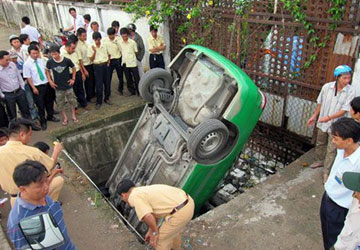 Chiếc taixi của hãng Mai Linh gặp nạn đầu cắm ngược xuống hố nước thải.
