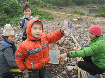 Cháu Đoàn Hải Long (6 tuổi - con ông Đoàn Văn Quý) reo lên khi tìm thấy một trang sách bị cháy dở